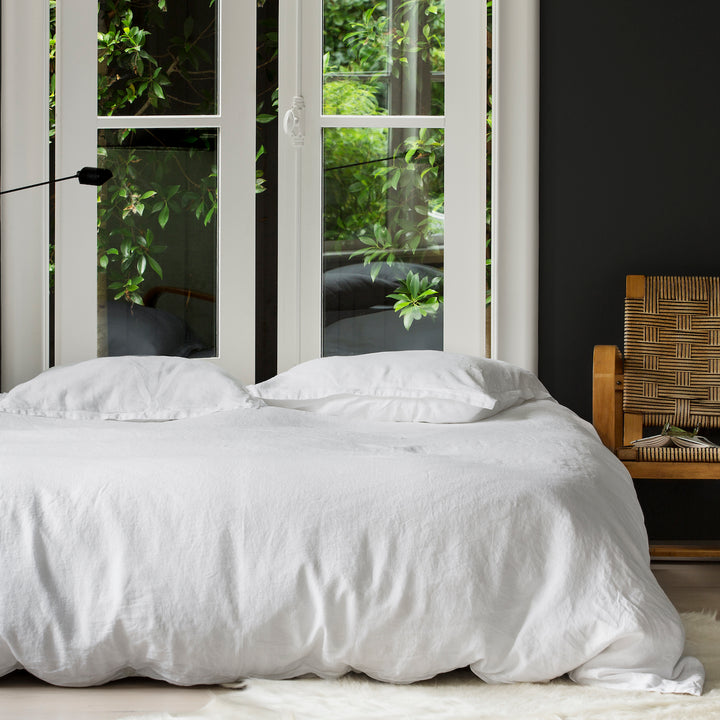 A bed dressed with White bedlinen, contrasting charcoal walls and large windows. Sizes: Queen, King, Super King