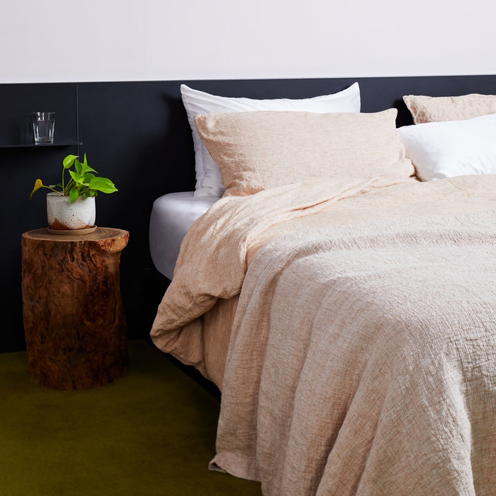 A bed dressed in Cinnamon and White bed linen, styled with a wooden bedside table and pot plant. Sizes: Queen, King, Super King