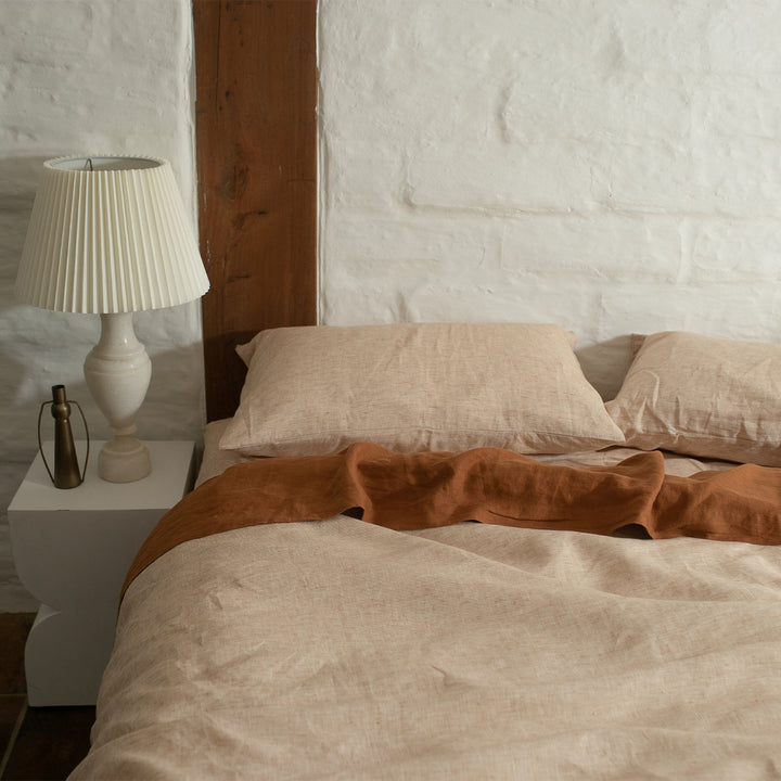 A bed dressed in Cinnamon and Cedar bed linen, styled with a modern white bedside table and cream lamp. Sizes: Queen, King, Super King