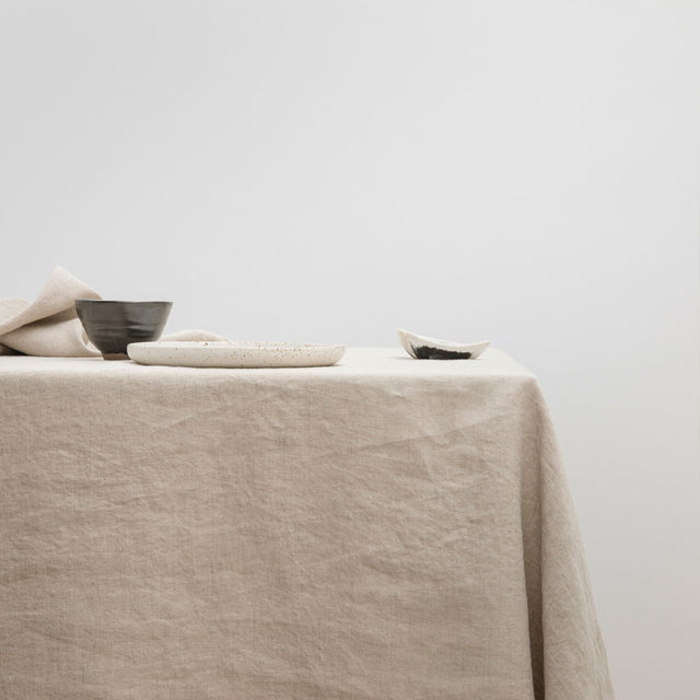 The Linen Tablecloth in Natural styled with various ceramic objects.