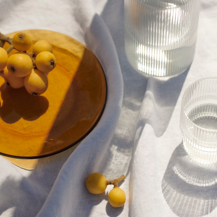 Close up of table setting with Tablecloth -White, with contrasting amber glass.