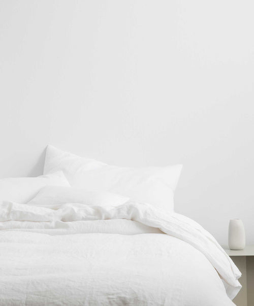 White linen duvet cover set on bed with soft texture and mother of pearl button closure in minimalist bedroom setting.