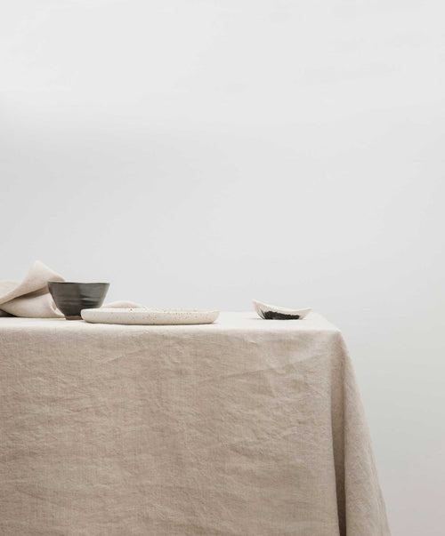 Dining Edit - Natural & White linen tablecloth with simple ceramic dishware in a soft, airy setting The beauty of home