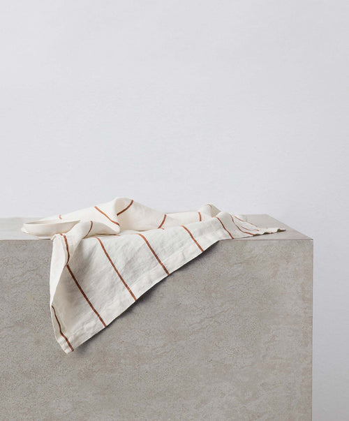 Dining Edit - Natural & Cedar Stripe linen napkin casually draped over stone surface The beauty of home