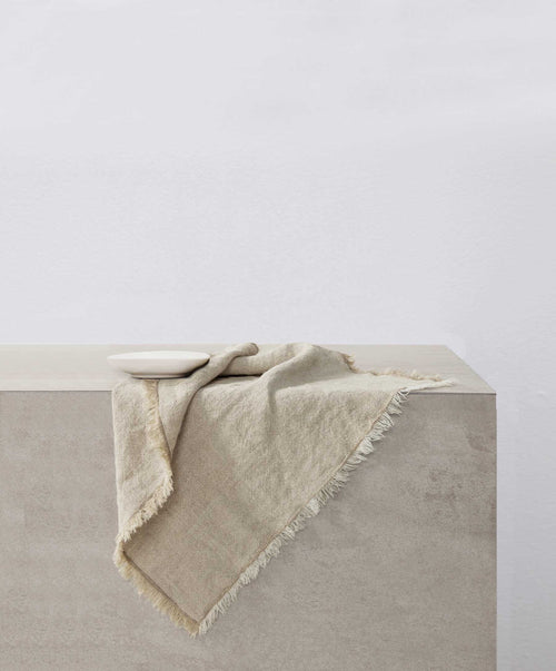 Dining Edit - Natural Fia Dining linen draped over neutral stone surface with soft natural texture The beauty of home