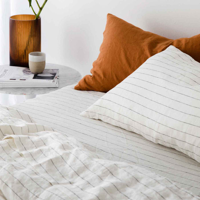 A bed dressed in Pencil Stripe bedlinen, with contrasting Pillowcases in Cedar.					