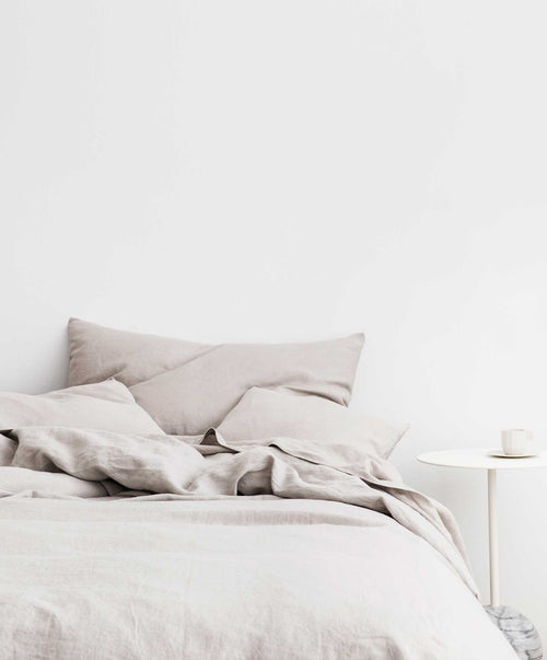 Linen Duvet Cover Set in smoke grey with soft texture styled on bed beside minimalist white side table with cup
