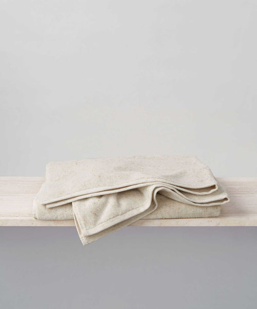 Speckle Bath Sheet folded on light wooden surface showcasing soft, breathable linen with natural texture The beauty of home