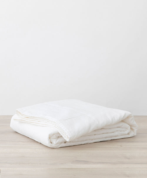 Quilted Bedcover - White folded on wooden surface showcasing premium natural linen The beauty of home