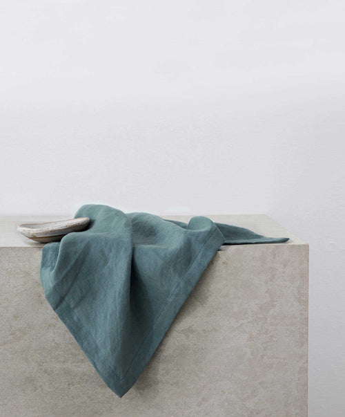 Linen Table Napkins - Bluestone gently folded on a textured stone surface showcasing natural breathable linen The beauty of home