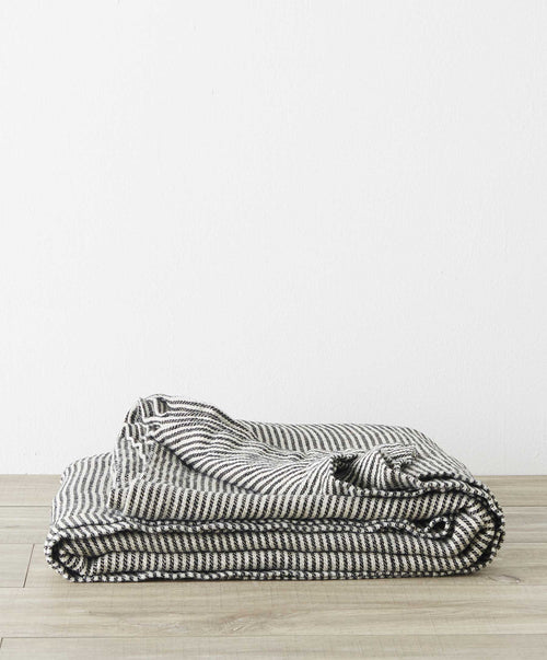 Mira Linen Bedcover - Ellis Stripe folded neatly on wooden floor, showcasing soft, breathable linen The beauty of home