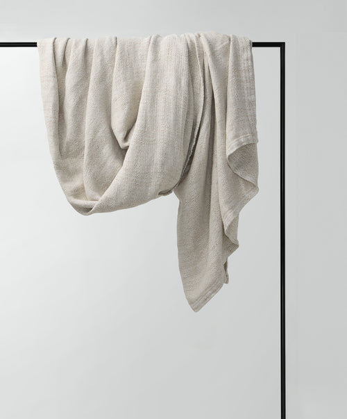 Luna Throw draped on black rail showcasing breathable, natural European Flax™ linen fabric The beauty of home