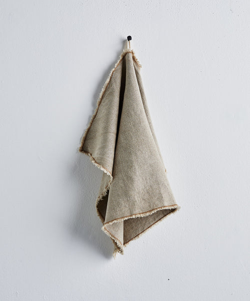 Fia Kitchen Towel - Bronze hanging simply against a plain white wall showing natural linen texture The beauty of home