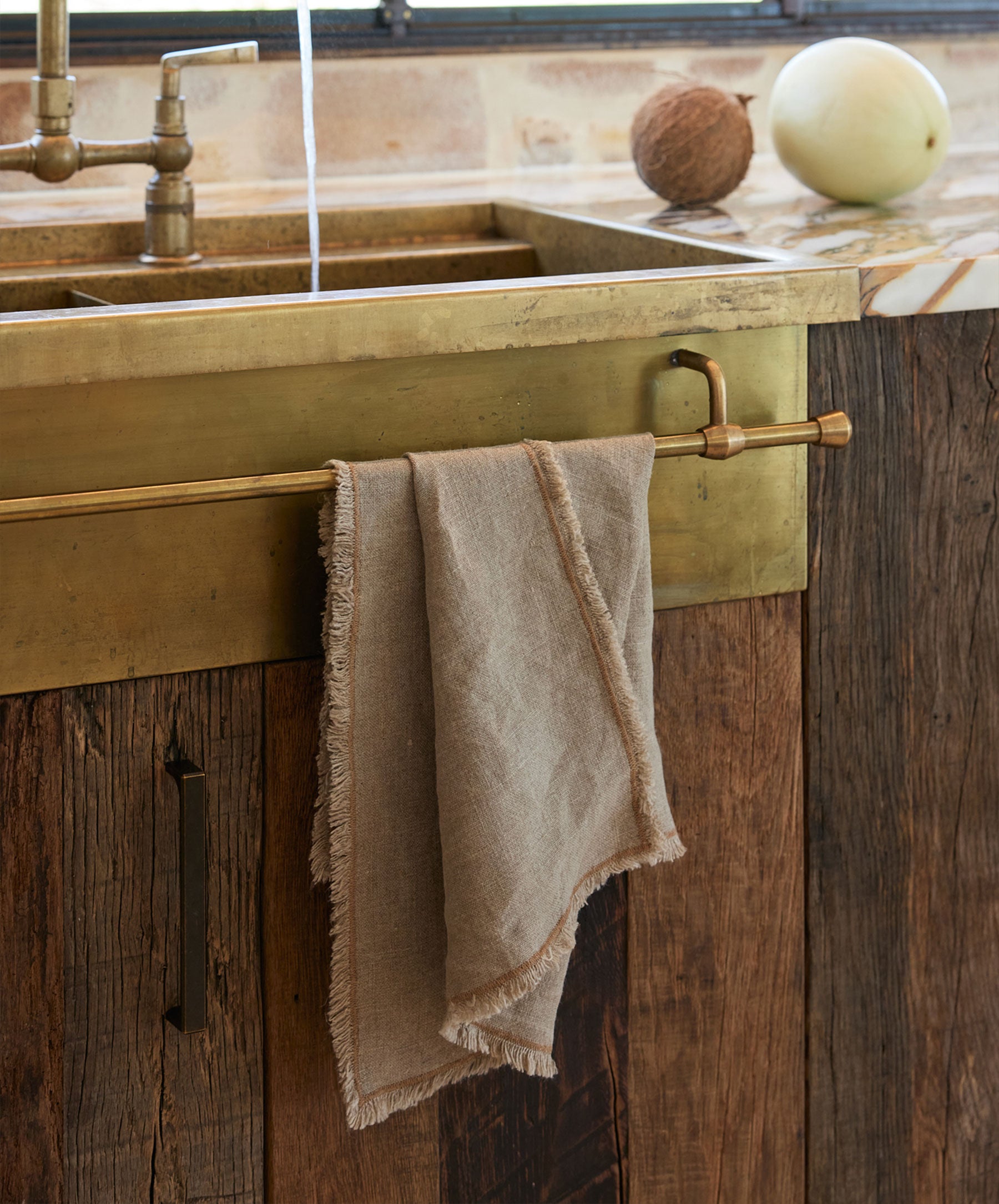 Fia Kitchen Towel - Bronze draped over brass rail in rustic kitchen setting with natural warm tones The beauty of home