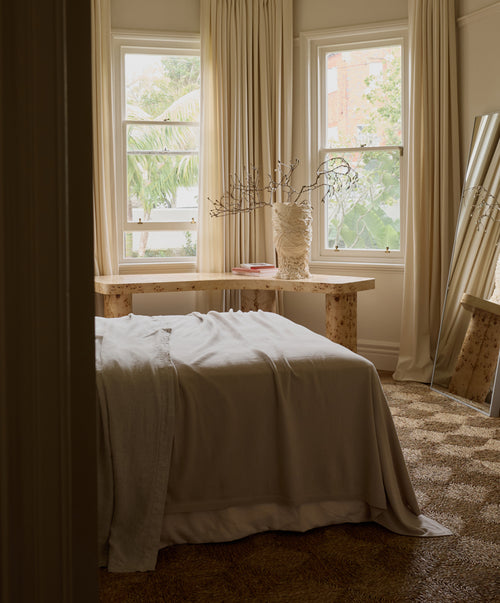 100% NZ Merino Wool Blanket - Oatmeal draped over bed in softly lit, neutral-toned bedroom with natural decor.