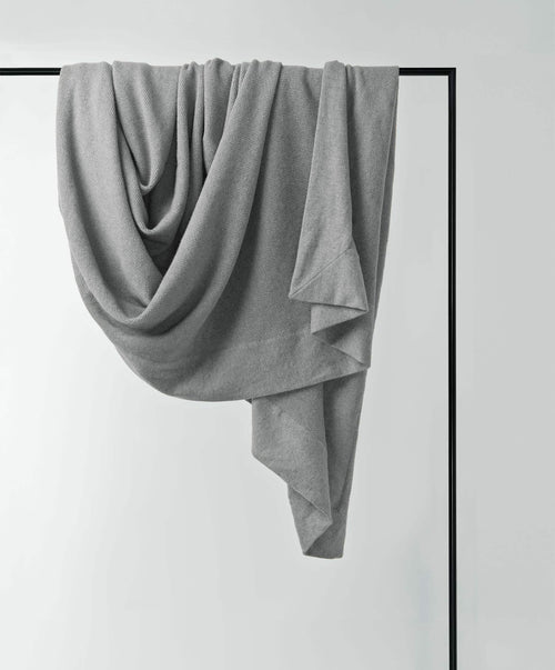 Gray fabric draped over a black rod against a white background