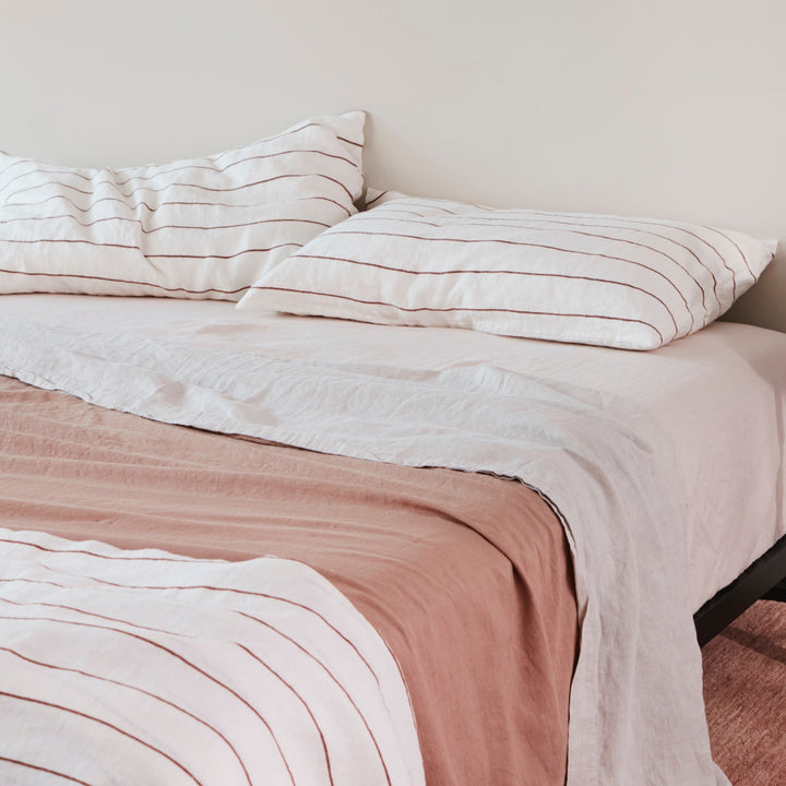 A bed dressed in Cedar Stripe, Blush, Smoke Grey and Fawn bed linen. Sizes: Queen, King