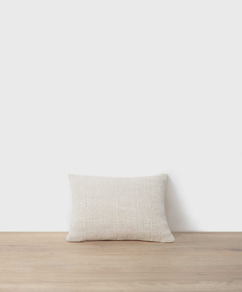 Luna Mini Cushion in natural woven linen resting on wooden surface against soft neutral background The beauty of home
