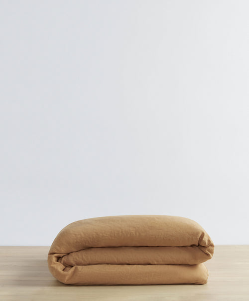 Linen Duvet Cover - Sand folded neatly on natural wood surface showcasing breathable sustainable linen The beauty of home