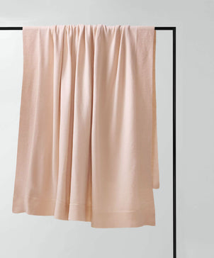 Pink towel draped over a black rack on a light gray background