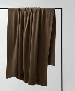 Brown blanket draped over a black frame on a light gray background