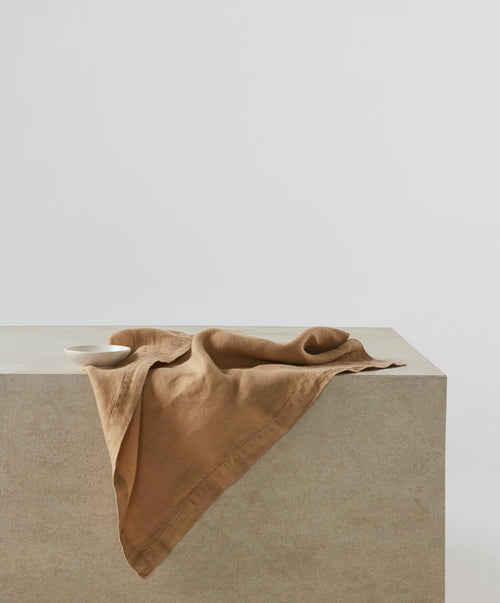 Linen Table Napkins - Sand draped over stone surface showcasing soft, natural fabric The beauty of home