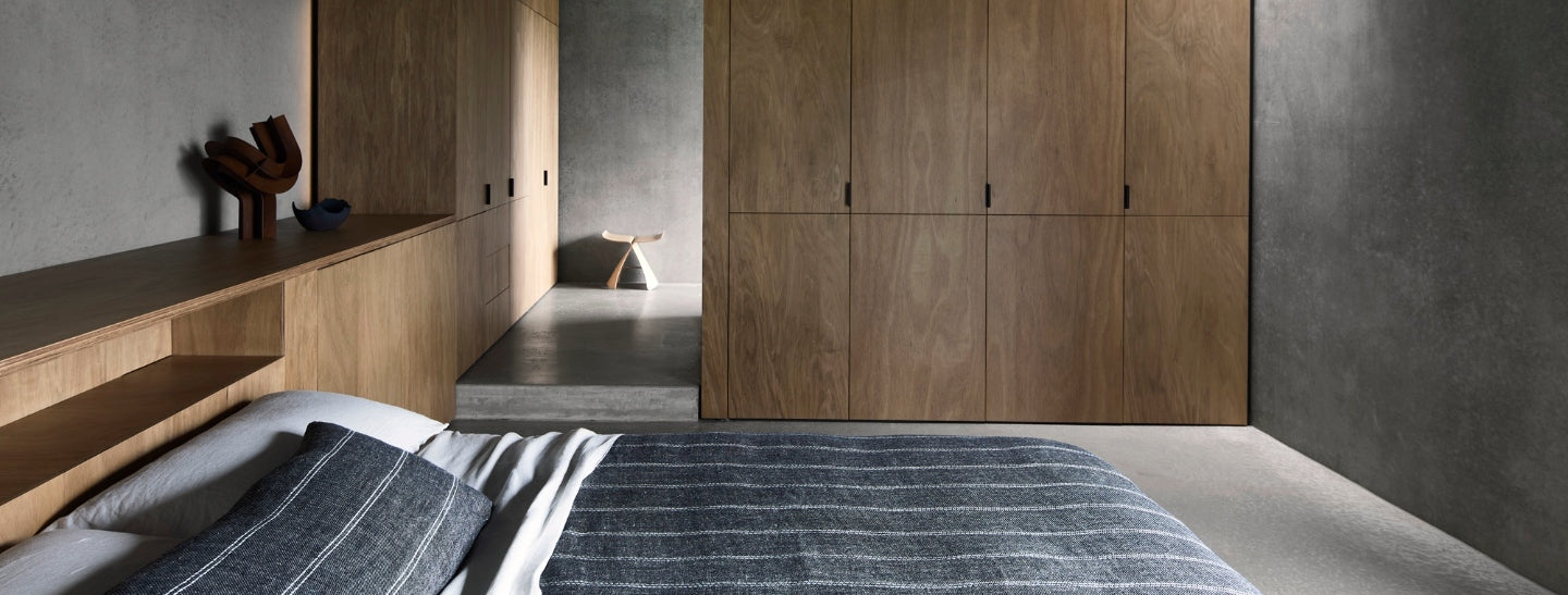 Modern bedroom with wooden wardrobes and a bed with striped bedding.