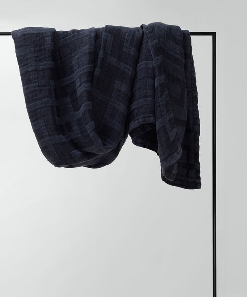 Dark blue towel draped over a black metal rod on a light gray background