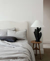 A boucle bed frame styled with linen piped sheet smoke sheet and a slate pillow. 