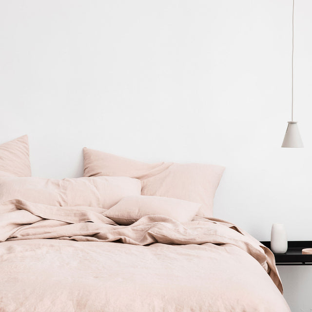 Bed styled with Blush duvet cover set and Blush sheet set. A lamp hangs from the ceiling, and on the black bedside table is a white ceramic vase. Sizes: Single, Double, Queen, King