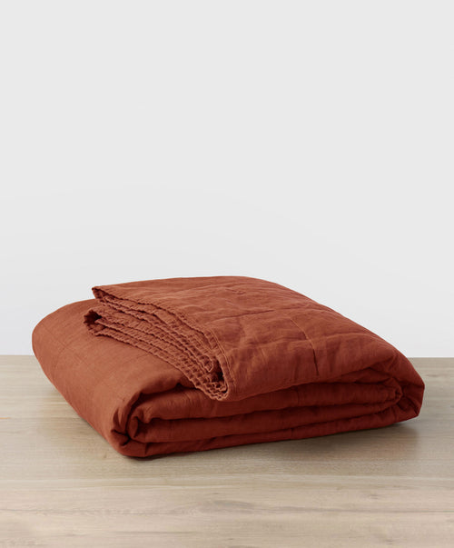 Quilted Bedcover - Sienna folded on a light wood surface highlighting natural linen texture and warmth The beauty of home