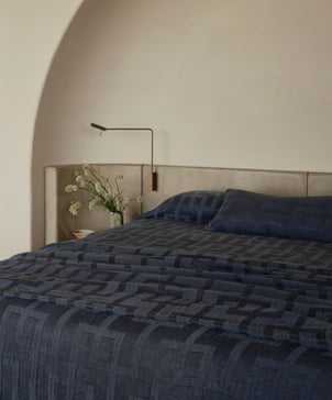 Bed with dark blue bedding in a bedroom setting