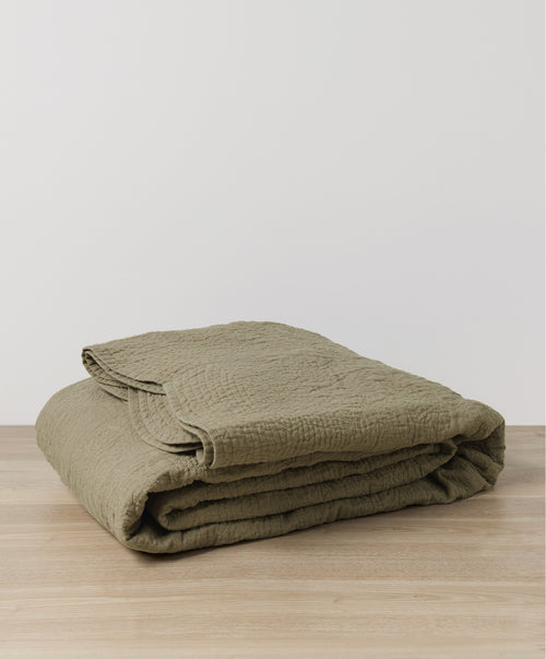Willow Embroidered Quilt - Putty folded on natural wood surface, showcasing breathable European Flax™ linen The beauty of home