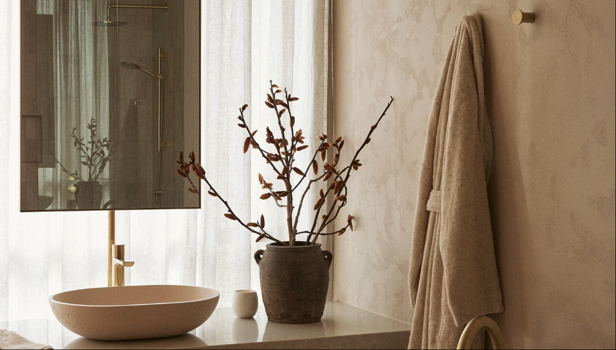 Bathroom interior with a sink, towel, and decorative plant.