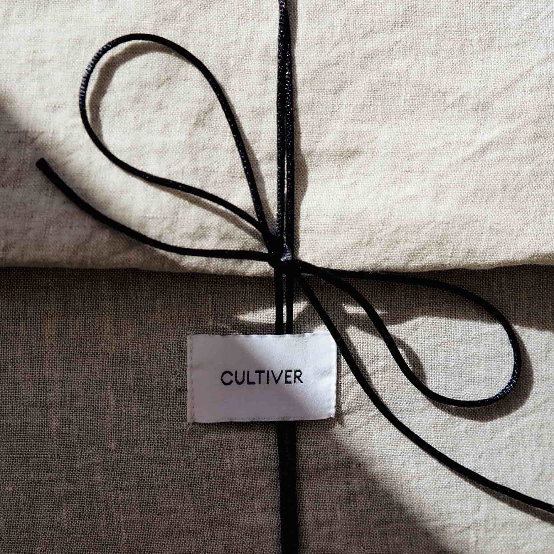 Product with 'Cultiver' label tied with black string on a textured surface