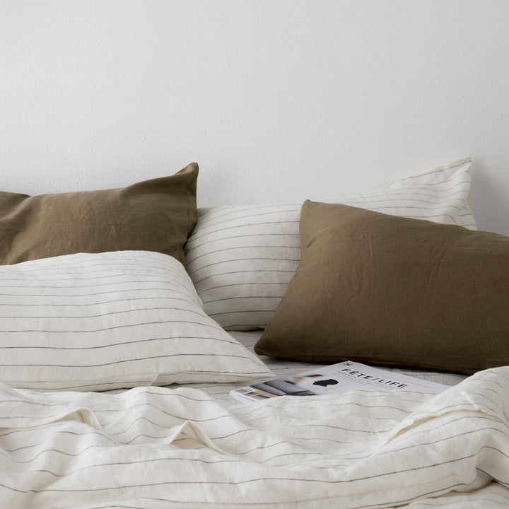 A close up of Olive and Pencil Stripe bed linen, styled with a magazine. Size: Single, Double, Queen, King