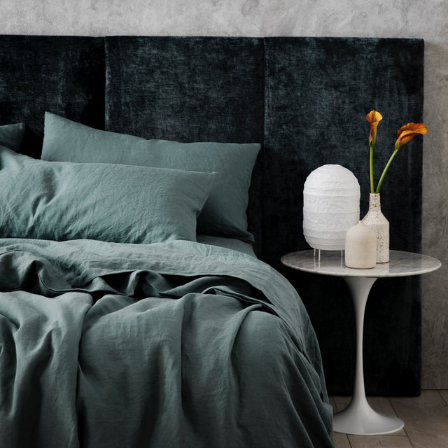 A bed dressed in Bluestone bed linen, styled with a dark blue velvet headboard and white modern bedside table. Size: Single, King Single, Double, Queen, King, Extra Deep King, Super King