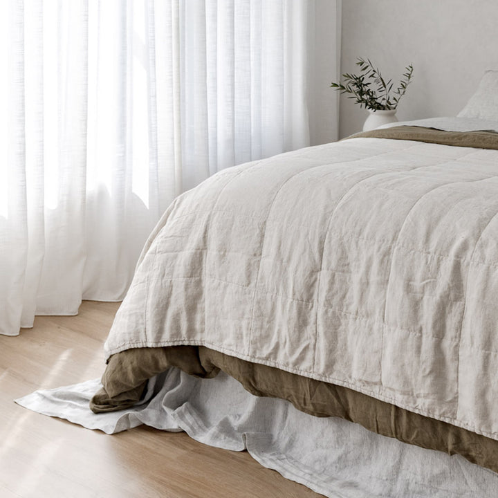 A cropped photo of a bed dressed in Olive, Natural and Pinstripe bed linen