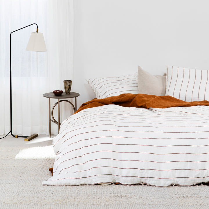  A bed dressed in Cedar Stripe and Cedar bed linen, styled with a European Pillowcase in Natural