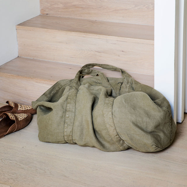 A Frankie Linen Bag in Olive sitting a the bottom of a staircase next to a pair of shoes